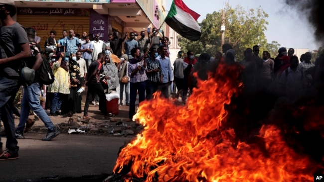 FILE - People chant slogans and burn tires during a protest to denounce the October 2021 military coup, in Khartoum, Sudan, Jan. 6, 2022.