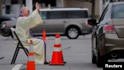 Pastor Brian Mahoney melayani jemaatnya secara "drive thru" di lapangan parkir gerejanya di gereja Katholik St. Mary, Chelmsford, Massachusetts, AS (foto: ilustrasi). 