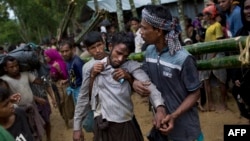 Kifawet Ullah is helped by other newly arrived Rohingya after he collapsed while waiting to have his token validated in order to collect a bag of rice distributed by aid agencies in Kutupalong, Bangladesh, Sept. 9, 2017.