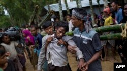 Kifawet Ullah is helped by other newly arrived Rohingya after he collapsed while waiting to have his token validated in order to collect a bag of rice distributed by aid agencies in Kutupalong, Bangladesh, Sept. 9, 2017.
