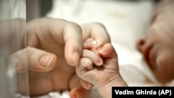 A newborn baby holds his mother's hand at the intensive care unit of the Marie Curie Children's Hospital in Bucharest, Romania, 2012. (AP Photo/Vadim Ghirda)