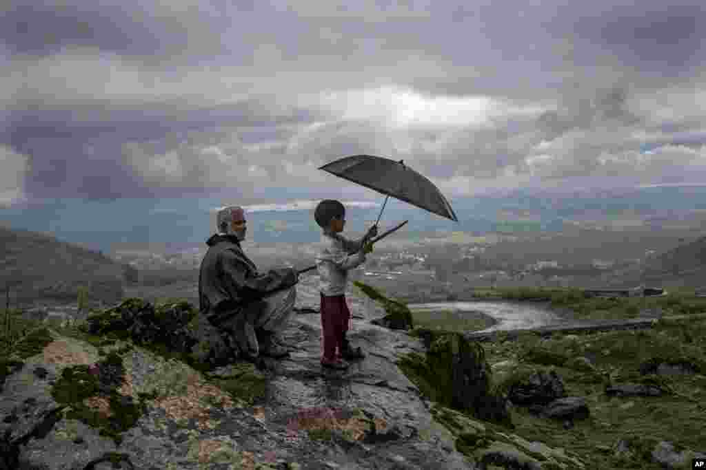 Ali Mohammad, a Kashmiri villager, with his grand son Burhan Ahmed keep an eye on their cattle from a hillock on the outskirts of Srinagar, Indian controlled Kashmir.