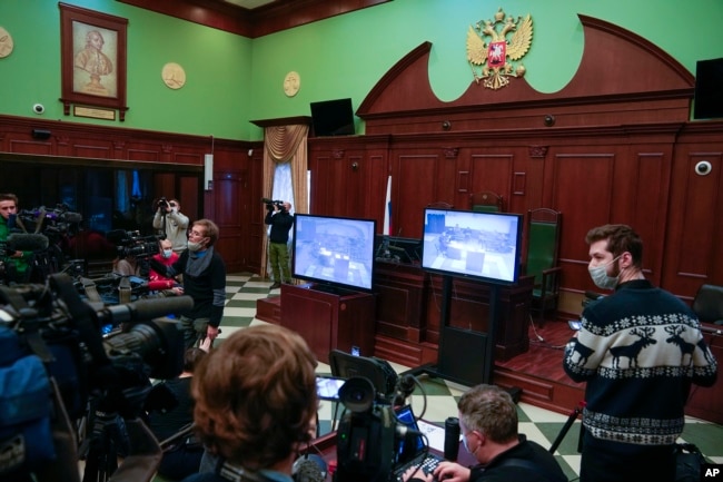 Journalists watch TV showing hearings on the liquidation of Council of Human Rights Center Memorial in the Moscow Court in Moscow, Russia, Wednesday, Dec. 29, 2021. (AP Photo/Alexander Zemlianichenko)