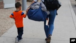 Three-year-old Jose Jr., from Honduras, is helped by representative of the Southern Poverty Law Center as he is reunited with his father Tuesday, July 10, 2018, in Phoenix.