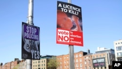 FILE - In this photo taken May 17, 2018, pro and anti-abortion poster's on lampposts, in Dublin. In homes and pubs, on leaflets and lampposts, debate rages in Ireland over whether to lift the country's decades-old ban on abortion.