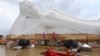 Buddhist monks paddle a boat through floodwaters in front of a reclining Buddha at the Wat Satue in Ayutthaya province north of Bangkok, Thailand, Monday, Oct. 4, 2021. 