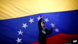 یکی از جوانان مخالف دولت، پرچم ونزوئلا را در یکی از خیابان های پایتخت نصب کرده است.