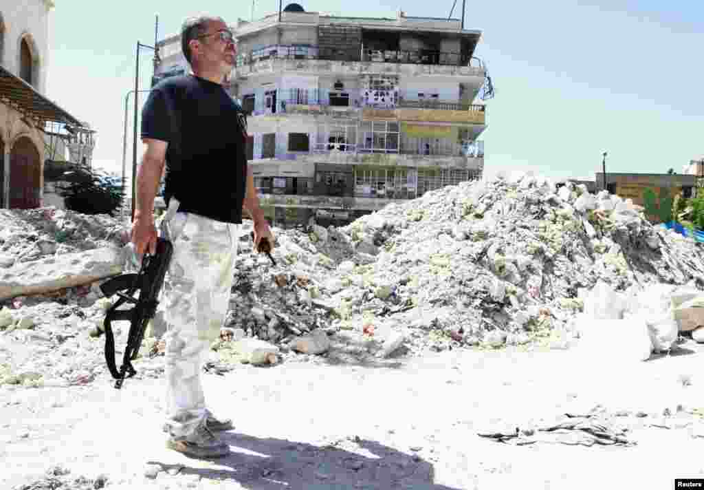 A Free Syrian Army fighter carries his weapon as he stands on rubble of damaged buildings in al-Aseela neighborhood near Aleppo's historic citadel, Sept. 13, 2013.