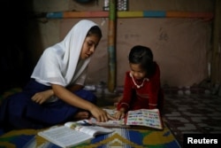 Yasmin, a Rohingya girl who was expelled from Leda High School for being a Rohingya, helps her younger sister to study in Leda camp in Teknaf, Bangladesh, March 5, 2019. REUTERS/Mohammad Ponir Hossain