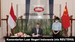 Menteri Luar Negeri Wang Yi menandatangani buku tamu saat Menteri Luar Negeri Retno Marsudi berdiri di sampingnya saat rapat di Jakarta, 13 Januari 2021. (Foto: Kementerian Luar Negeri Indonesia via REUTERS)