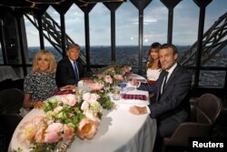 FILE - Brigitte Macron, left, wife of French President Emmanuel Macron, right, U.S. President Donald Trump and first lady Melania Trump pose at their table at the Jules Verne restaurant for a private dinner at the Eiffel Tower in Paris, July 13, 2107.