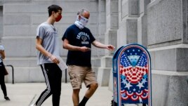 Benjamin Graff, center, and his son Jacob Graff, 19, drop off their mail-in ballots for the Pennsylvania primary election, in Philadelphia, Tuesday, June 2, 2020. (AP Photo/Matt Rourke)
