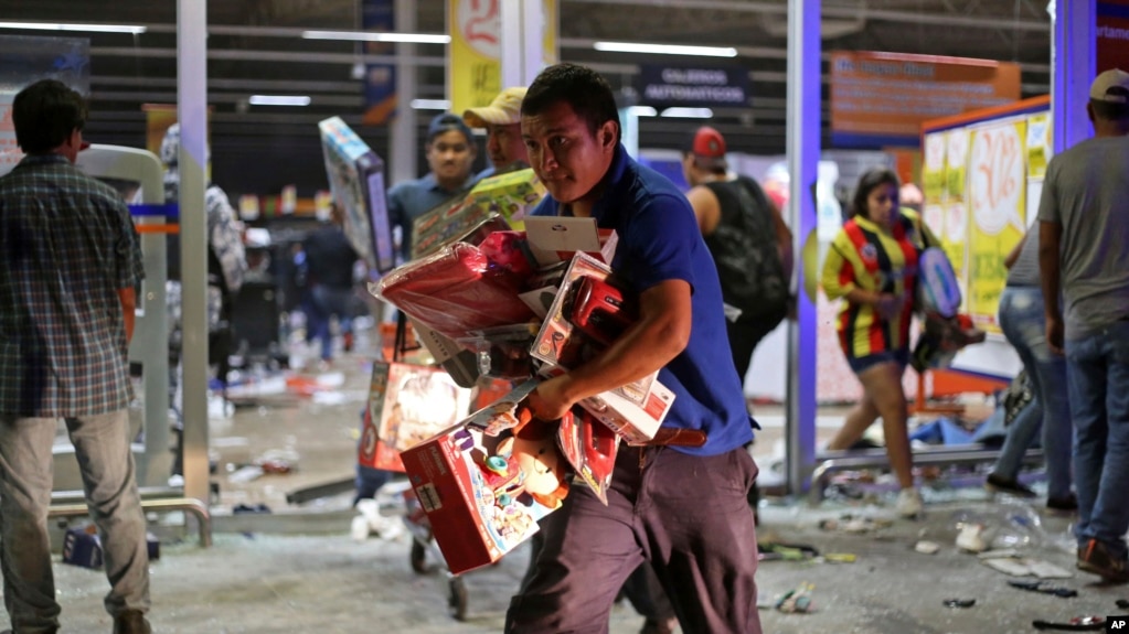 FILE - A man runs with toys as a store is ransacked by a crowd in the port of Veracruz, Mexico, Wednesday Jan. 4, 2017.