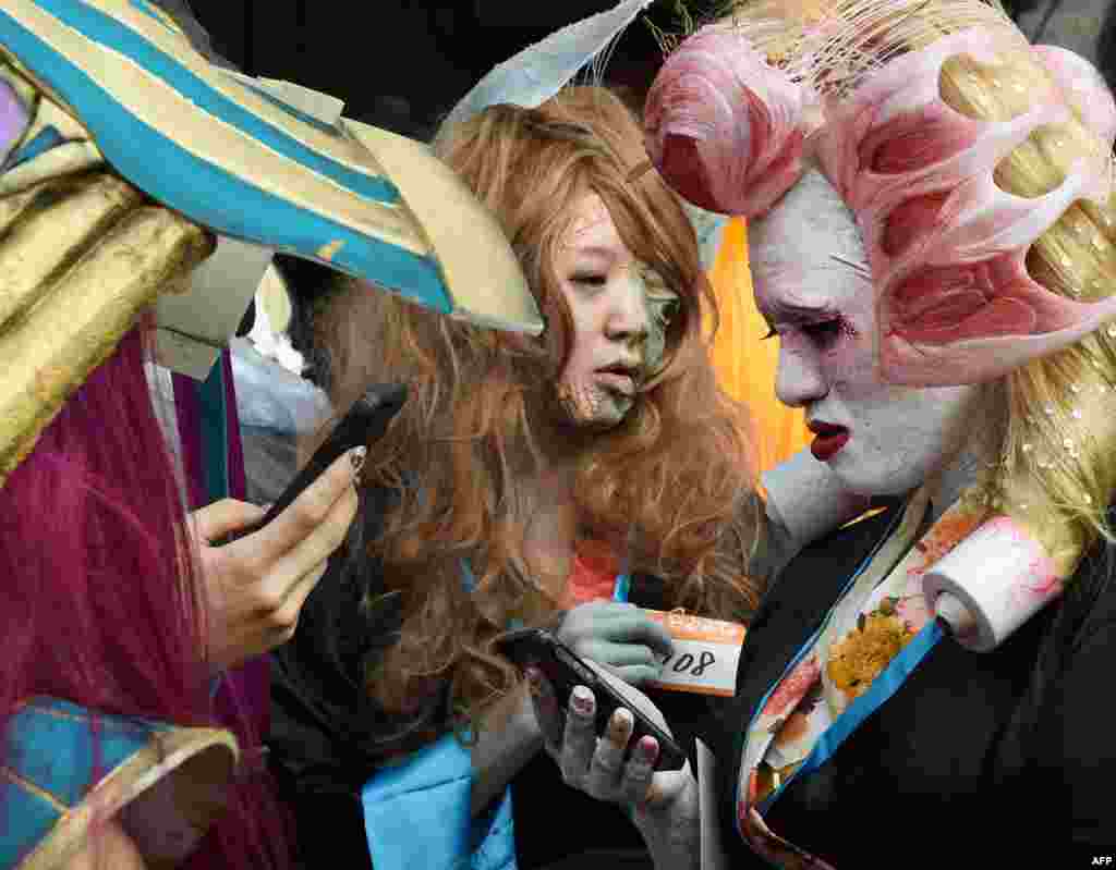 Participants dressed in costumes use their phones as they wait for the Halloween Parade in Kawasaki, a suburb of Tokyo, Japan.