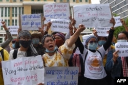 Supporters of Rong Chhun, leader of the Cambodian Confederation of Unions hold placards during a protest in front of Phnom Penh municipal court on August 1, 2020. (Photo by TANG CHHIN Sothy / AFP)