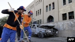 Workers sweep away debris after a bombing in Baghdad, Iraq, 23 Jan 2011.