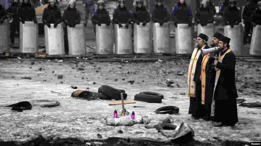 Un prêtre parle à travers un mégaphone à la police antiémeute et aux manifestants anti-gouvernementaux sur le site de récents affrontements à Kiev 12 Février 2014.