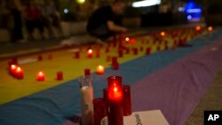 FILE - Man lights candles atop rainbow flag in solidarity with Pulse Orlando victims, Madrid, Spain, June 12, 2016.