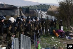 FILE - Macedonian policemen guard the borders of their country as an army truck arrives to build a border fence to prevent illegal crossings by migrants, in the Greek-Macedonian border near the Greek village of Idomeni, Nov. 28, 2015.
