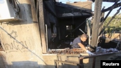 یک مامور پلیس در حال تحقیق از آثار به جا مانده از آتش سوزی عمدی خانه‌ای در یک روستای کرانه باختری - ۹ مرداد ۱۳۹۴ 