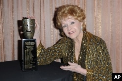 FILE - Debbie Reynolds, shown with her SAG Lifetime Achievement Award in January 2015, rose to fame in 1952's "Singin' in the Rain" and earned an Oscar nomination for 1964's "The Unsinkable Molly Brown."