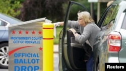 Seorang perempuan mencoba memasukkan surat suaranya ke dalam kotak suara di salah satu TPS di Rockville, Maryland, 2 Juni 2020. (REUTERS / Kevin Lamarque)