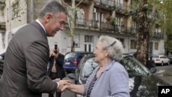 FILE - Montenegrin leader Milo Djukanovic talks to a supporter in front of a polling station in downtown Podgorica, Oct. 14, 2012.