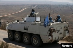 Members of the United Nations Disengagement Observer Force (UNDOF) ride on an armoured personnel carrier (APC) in the Israeli-occupied Golan Heights before crossing into Syria, Aug. 31, 2014.