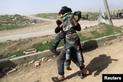 A man carries his relative, injured while opening a booby-trapped shop in Tayaran district, as Iraqi forces battle with Islamic State's fighters in western Mosul, Iraq, March 12, 2017.