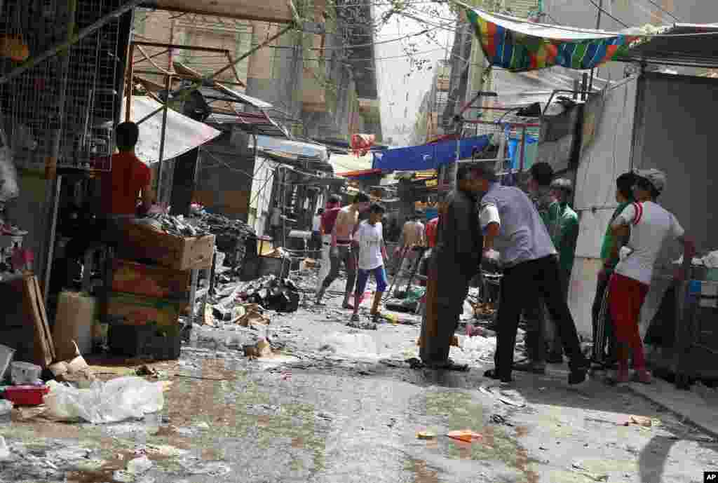 After a bomb hidden in a wooden cart exploded near a Shiite mosque in one of Baghdad's largest markets, civilians inspect the site of the attack, in Shorja Market in Baghdad, Iraq, July 17, 2014.