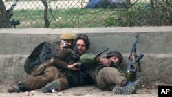 Indian police men take cover during a gun battle in Srinagar, India, Mar. 13, 2013.