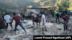 Des personnes pataugent dans une zone inondée à Dipayal Silgadhi, au Népal, le jeudi 21 octobre 2021.