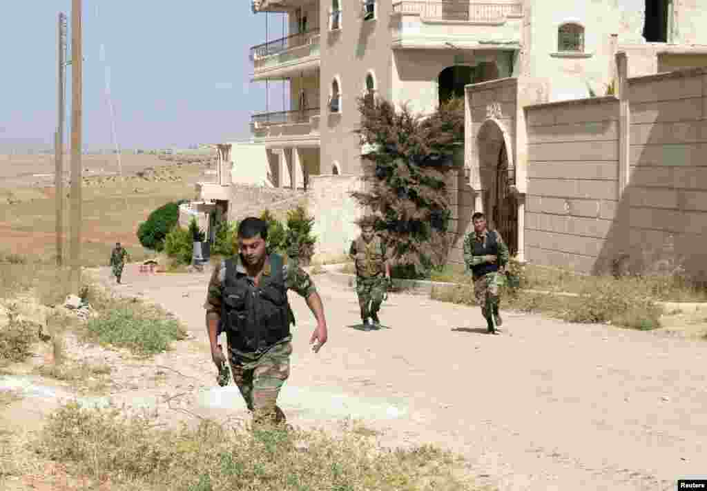 Forces loyal to Syria's President Bashar al-Assad carry their weapons in al-Mansoura, in the Aleppo countryside, June 3, 2013.