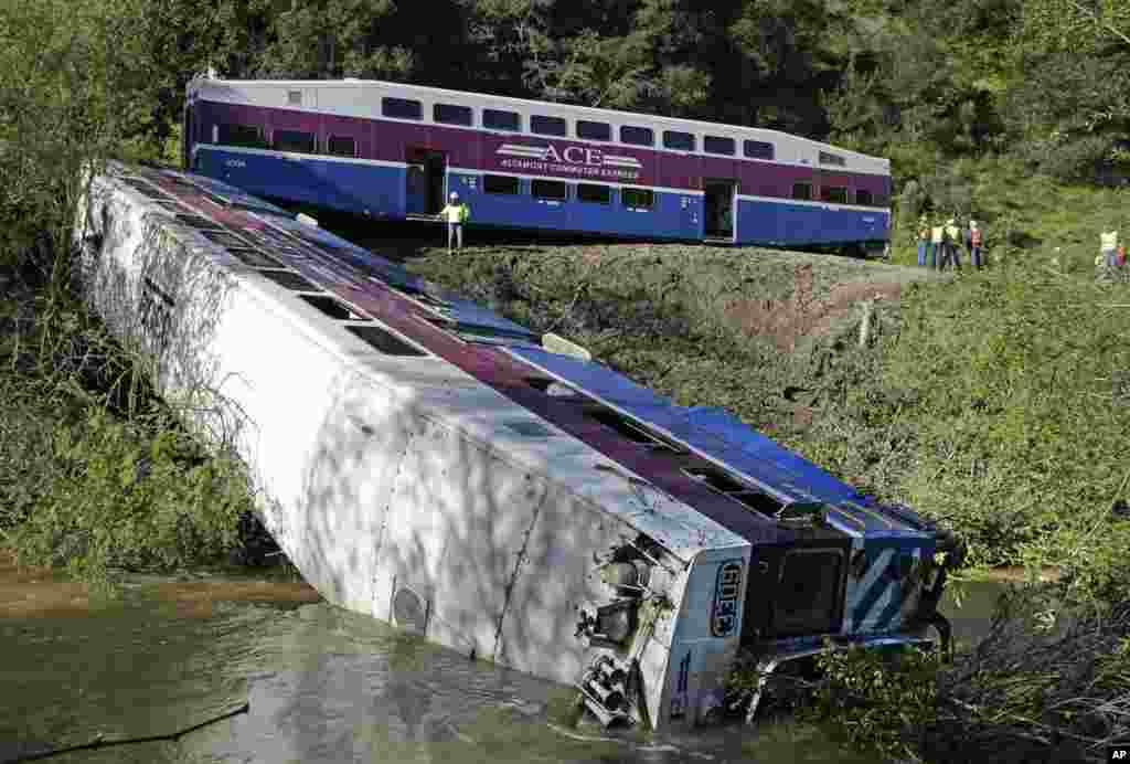 Para pekerja memeriksa kereta ekspres di Sunol, California yang tergelincir keluar dari relnya, diduga akibat tanah longsor menyebabkan batang pohon menghalangi jalur kereta.