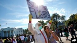 2014年10月17日，有群眾在白宮外示威，抗議政府對伊波拉疫情的處理，標語牌上寫的是“停止民航班機”
