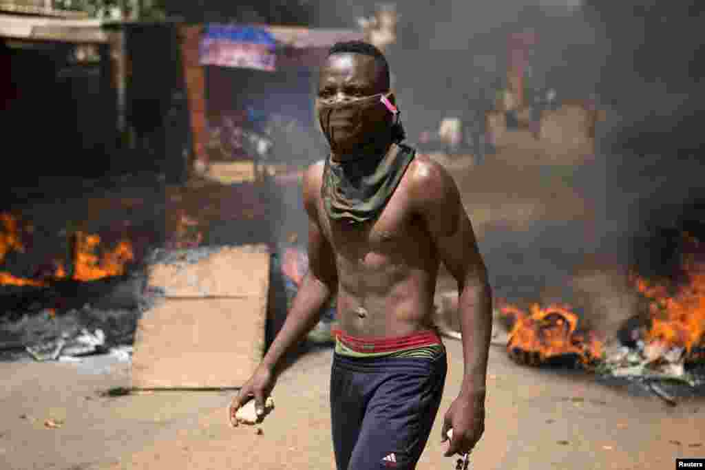 Un manifestant &nbsp;a des pierres dans ses mains sur une route barricadée à Ouagadougou, capitale de Burkina Faso, le 28 octobre 2014. La police a lancé des grenades à gaz lacrymogène aux&nbsp; manifestants qui ont usé des pierres à la fin d&rsquo;une manifestation qui avait regroupé des dizaines de milliers de gens. REUTERS/Joe Penney 