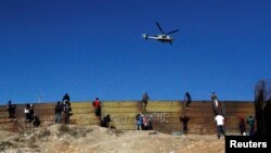 25일 멕시코 티후아나에서 중남미 출신 이민자들이 미국으로 넘어가기 위해 불법월경을 시도하고 있다. 