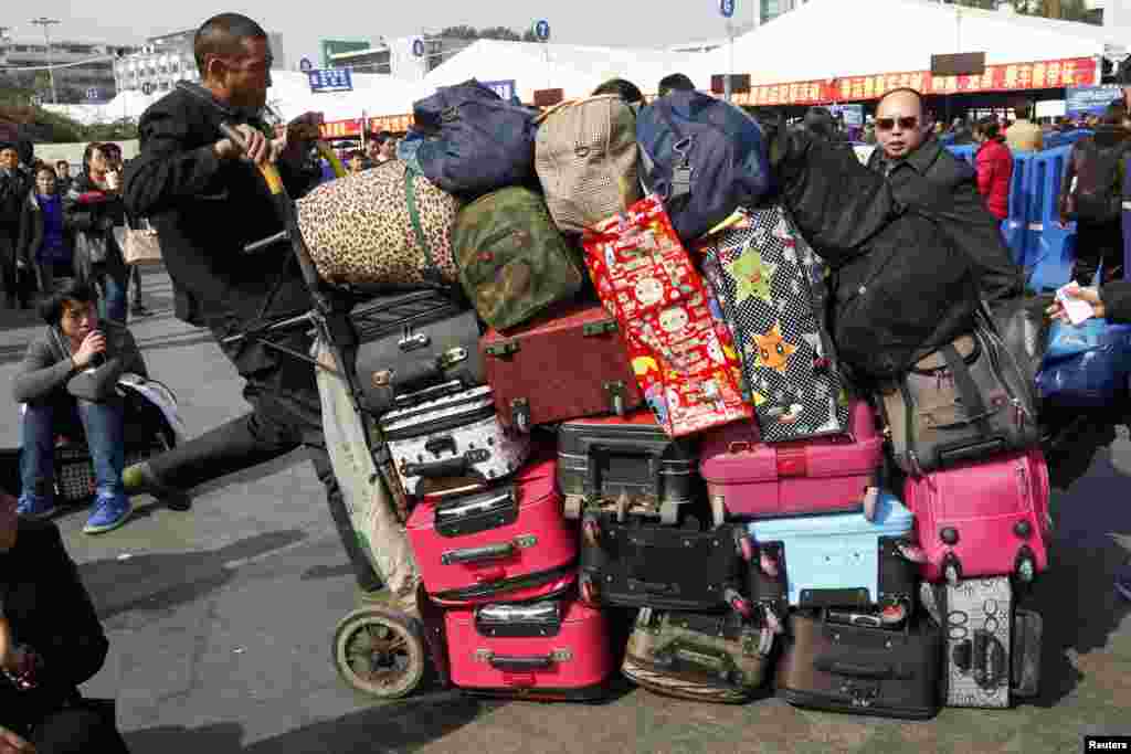 A man pushes a cart carrying passengers' luggage outside a railway station in Guangzhou, Guangdong province, China, Jan. 15, 2014, during the 40-day Spring Festival travel rush.