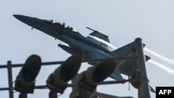 This U.S. Navy photo obtained Sept. 24, 2014 shows an F/A-18F Super Hornet attached to the Fighting Black Lions of Strike Fighter Squadron (VFA) 213 as it flies over the aircraft carrier USS George H.W. Bush.
