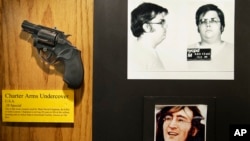 FILE - The gun used by Mark David Chapman to kill John Lennon is displayed next to their pictures at a small museum in the Forensic Investigation Division of the New York Police Department in New York, Dec. 8, 2015. 