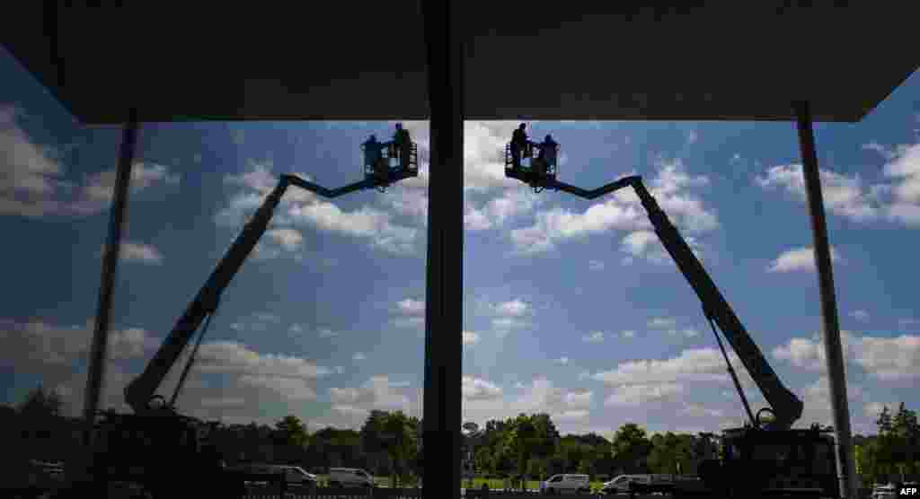 Workers on a mobile crane are reflected in the glass facade of the Paul-Loebe-Haus parliamentary annex amid preparations to host the swearing-in ceremony of Germany&#39;s new defense minister on July 24, 2019.