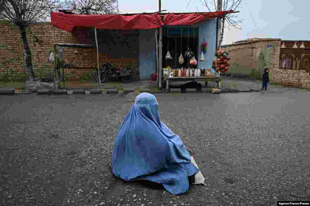 A woman wearing a burqa begs on a street in Mazar-i-Sharif, Afghanistan.