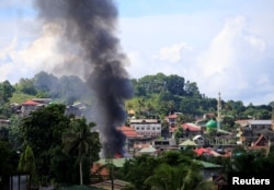 FILE - Smoke billowing from a burning building is seen as government troops continue their assault on insurgents from the Maute group, who have taken over large parts of Marawi City, Philippines, June 1, 2017.