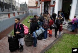 Venezuelan migrants wait outside their country’s embassy for a bus that will transport them to the airport, in Lima, Peru, Aug. 27, 2018.