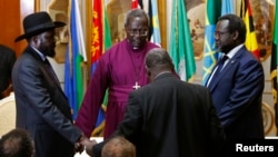 FILE - South Sudan's rebel leader Riek Machar (R) and South Sudan's President Salva Kiir (L) hold a priest's hands before signing an earlier peace agreement in Addis Ababa, May 9, 2014.