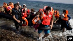 Jango from Syria carries his daughter Varia , no surname available, as they arrive aboard a dinghy after crossing from Turkey to the island of Lesbos, Greece, Sept. 8, 2015. 