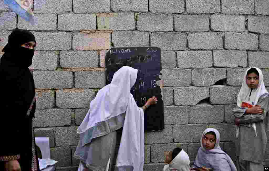 A Pakistani student writes on a blackboard attached to a wall, during a match class at the EHD Foundation School, on the first International Day of the Girl Child, in Islamabad, Pakistan, October 11, 2012.