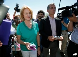 La alcaldesa de Seattle, Jenny Durkan, a la izquierda, y el alcalde de Los Ángeles, Eric Garcetti, llevan sandalias como regalo para los niños inmigrantes que están detenidos en una instalación en Tornillo, Texas, cerca de la frontera con México, el jueves 21 de junio de 2018. Alcaldes de más de un docena de ciudades de Estados Unidos, incluyendo Nueva York y Los Ángeles, se reunieron cerca de la instalación de detención para convocar a la reunificación inmediata de los niños inmigrantes con sus familias. (AP Photo / Andres Leighton)