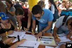 FILE - People sign a petition, organized by the opposition, to initiate a recall referendum against Venezuela's President Nicolas Maduro in Caracas, April 27, 2017.