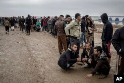 FILE - Iraqis displaced from Mosul receive aid distributions near Qayara, Iraq, Dec. 28, 2016.